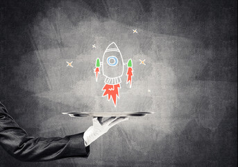 Wall Mural - Hand of waiter presenting sketched rocket on tray
