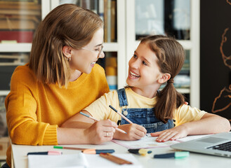 Wall Mural - Cheerful mother doing homework with daughter at home