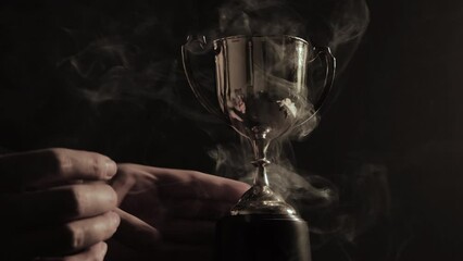 Wall Mural - man's hand holding a silver trophy after winning a match