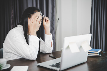 Wall Mural - Young business woman person sleepy and has frustration eye problems with cephalalgia disease from using laptop computer on her office desk. Stressed female employee tired and exhausted from overwork.