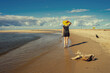 Dziewczyna w żółtym kapeluszu spacerująca po plaży. Pogodny słoneczny letni dzień, spokojna woda. 