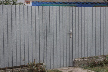 Poster - gray long metal fence wall and closed door in the rural street