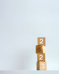 Poster - 2023 Happy New year vertical banner. Business goal with year numbers and target icon on wooden cube blocks stacked on white background with copy space. Welcome, Merry Christmas, and Happy New Year.
