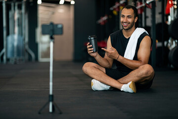 Handsome Black Male Fitness Blogger Recording Video Review For Sport Shaker Bottle