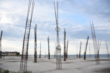 An Unfinished Construction Site With Protruding Reinforcement Bars And Concrete Against The Background Of The Sea Horizon On The Shore
