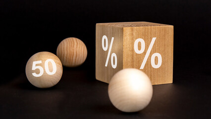 Wall Mural - percent sign on wooden cube on black background with wooden balls. number 50 on wooden ball, concept of sale and discount