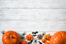 Halloween Background, Top View. Pumpkins And Sweets On White Wooden Table, Flat Lay.