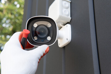 Poster - Close-up of surveillance camera installation, male hand holds cctv camera.