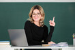 Portrait of teacher or female tutor working at table in college or high school. Young women student with pointing finger.