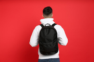 Wall Mural - Young man with stylish backpack on red background, back view