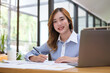 © wattana - Confident millennial female entrepreneur sitting in her personal office and smiling to camera.