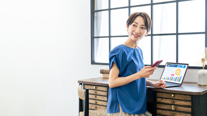 Leinwandbilder - おしゃれな室内でスマホとパソコンを使う女性