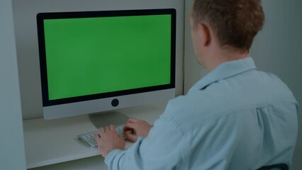 Poster - man sitting at the desk typing on keyboard computer with green screen working at home