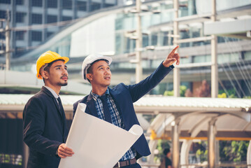 Civil engineer teams meeting working together wear worker helmets hardhat on construction site in modern city. Foreman industry project manager engineer teamwork. Asian industry professional team