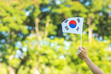 hand holding Korea flag on nature background. National Foundation, Gaecheonjeol, public Nation holiday, National Liberation Day of Korea and happy celebration concepts