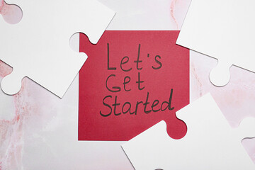 Paper sheet with text LET'S GET STARTED and puzzle pieces on light background