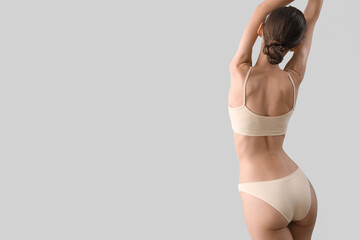 Wall Mural - Slim young woman in underwear on light background, back view