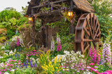 old classic water mill with colorful flower garden