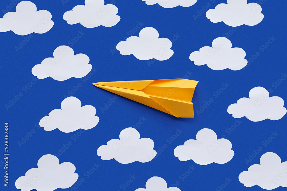 Yellow paper plane and clouds on blue background