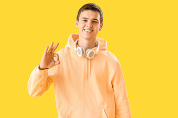 Poster - Teenage boy with headphones showing OK on yellow background