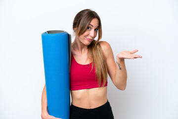 Wall Mural - Young sport woman going to yoga classes while holding a mat isolated on white background having doubts while raising hands