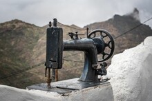 Vintage Sewing Machine On A Rocky Surface Against A Blurry Mountain