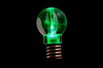 Sticker - Green illuminated light bulb on a black background