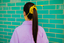 Ponytail Of Young Woman Tied With Yellow Cable In Front Of Wall