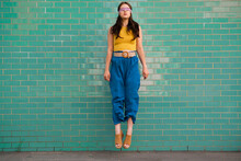 Woman With Blindfold Levitating In Front Of Brick Wall