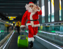 Man Wearing Santa Claus Costume Running With Suitcase On Moving Walkway At Airport