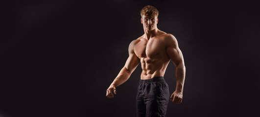  The torso of attractive muscular male body builder on black background.