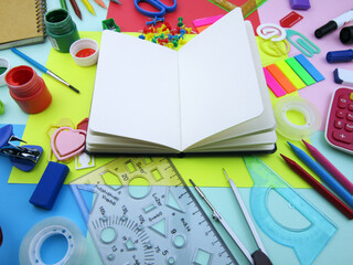  open notebook amid colorful school supplies   