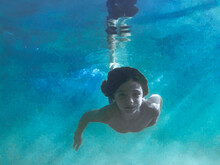 Young Boy Swimming Underwater With Sun Beams Through Water