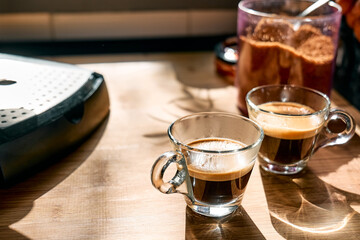 Two glass cups of aromatic hot drink espresso, prepared in espresso coffee machine in the kitchen at home. Awakening drink. Morning habit.