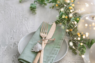  Christmas and New Year table setting with plate, gold cutlery, green linen napkin , candles, centreplace with gold bokeh. Festive dinner banner