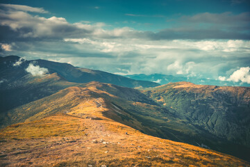 Wall Mural - tourist trekking trail on mountain range peak. autumn orange meadow and colorful cloudy aqua sky. aw