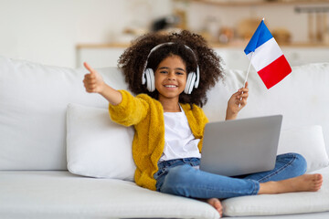 Happy black girl using laptop, showing French flag