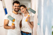 Portrait of young couple painting wall in their home.