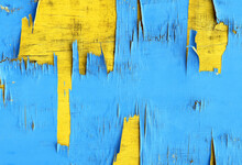 A Vibrant Abstract Of Blue Peeling Paint Revealing A Yellow Weathered Wood Texture Beneath. Colourful Pattern And Design.