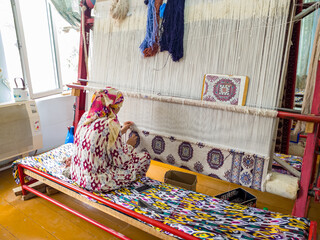 Hands of a woman are weaving carpet tools and threads handmade in Uzbekistan Samarkand Bukhara carpet, textile production folk traditional Muslim work