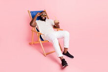 Full Size Portrait Of Carefree Peaceful Man Sit Comfy Chaise Lounge Enjoy Drink Isolated On Pink Color Background