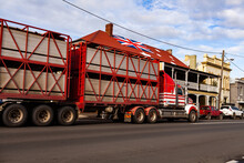 Red Cattle Truck Livestock Transport On Main Street Of Country Town In Australia Near Pub With Flag