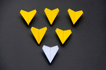 Wall Mural - White paper plane origami leading yellow planes on dark background. Leadership skills concept