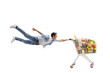 © Ljupco Smokovski - Full length shot of a casual young man flying and holding a shopping cart with food