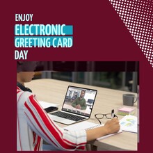Composition Of Enjoy Electronic Greeting Card Day Text Over Biracial Businessman Using Laptop