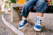 © Oleksandra - Baby feet in small blue lace-up sneakers. High quality photo