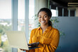 © Prostock-studio - Portrait of positive black female entrepreneur standing near window and using laptop computer, free space