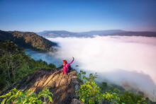 Young Woman In Red Jacket Hiking On Pha Muak Mountain, Border Of Thailand And Laos, Loei Province, Thailand.