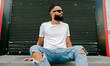 © San4ezz007 - Young bearded hipster guy wearing white blank t-shirt and blue jeans in a random urban style. Design men t shirt mock-up for print