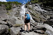 Girl wearing hiker clothes under the magnificent Nardis waterfalls in Val di Genova, Trentino Italy.